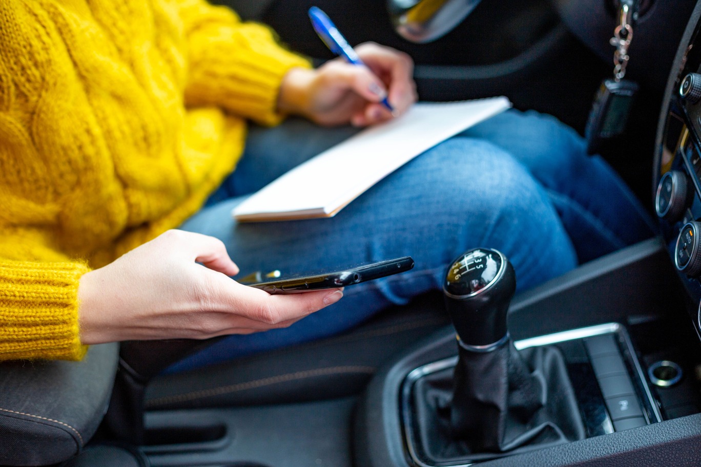 persona en el coche con libreta y teléfono